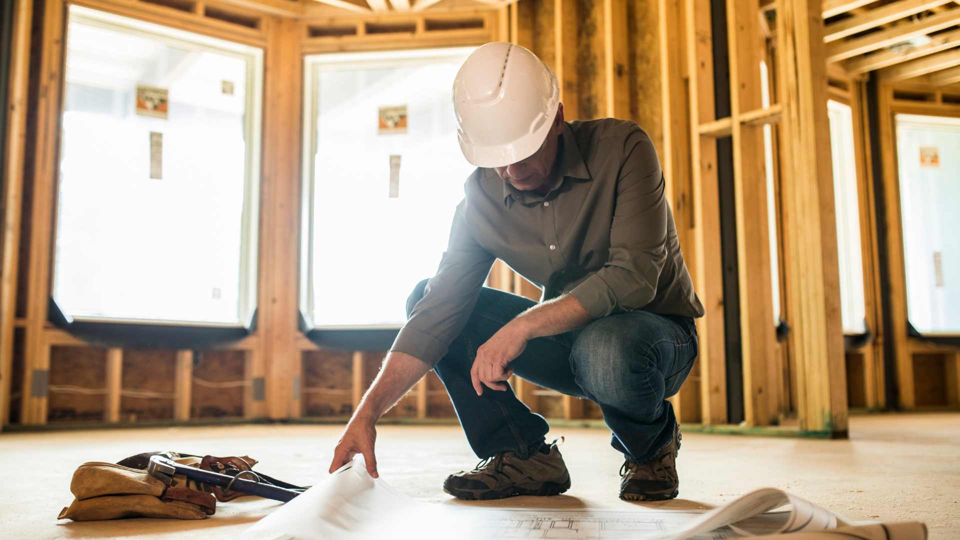 Builder reviewing plans inside a timber-framed new build